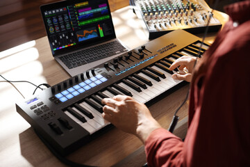 Man working with MIDI keyboard at wooden table indoors, above view