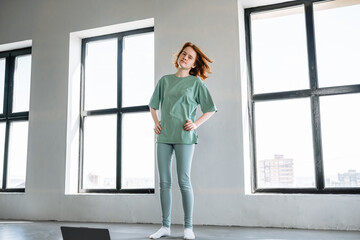 Young woman dancing joyfully in a bright, modern studio on a sunny day