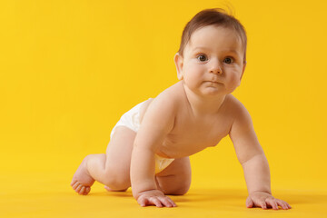 Cute little baby crawling on yellow background