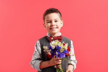 Portrait of smiling little boy with bouquet of beautiful flowers on red background