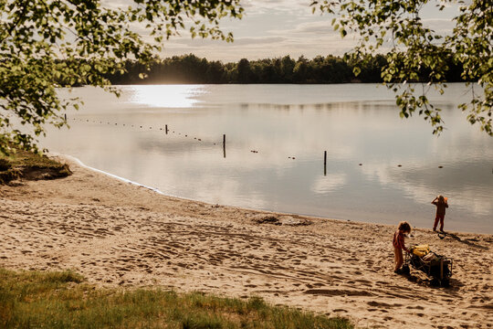 Children on a sandy lakeshore under soft golden sunlight