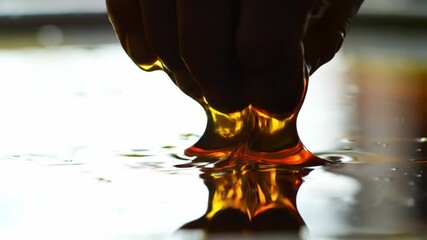 Stretching amber liquid with fingers  close up dark yellow color - Powered by Adobe