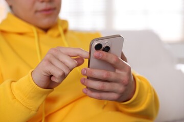 Teenage boy using smartphone at home, closeup