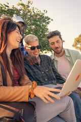 A diverse group of young students or freelancers collaborating outdoors on a laptop. Modern team...