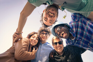 Low angle view of a happy diverse group of friends looking down at camera in a circle. Concept of...