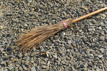 A close-up of a typical Indonesian stick broom lying on a pebble surface, depicting a traditional...