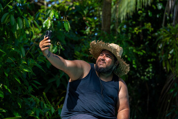 Latin American tourist taking a selfie with smartphone while lounging by the pool at a tropical...