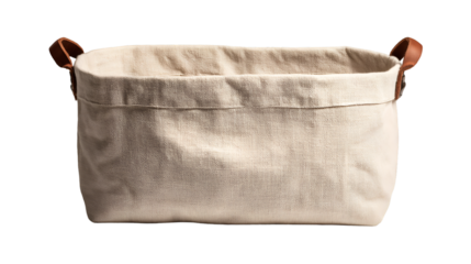 A close up of a rectangular beige fabric storage basket with brown leather handles on a black background