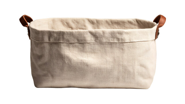 A close up of a rectangular beige fabric storage basket with brown leather handles on a black background