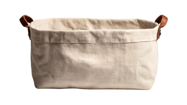 A close up of a rectangular beige fabric storage basket with brown leather handles on a black background