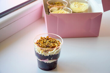 Delicate sweet desserts made of sponge dough and custard . Delicious desserts in transparent glasses of British cuisine in paper box. Close-up. Copy space. Selective focus.