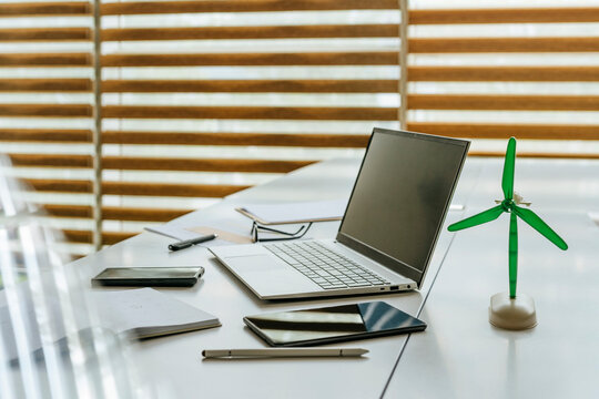 Modern office desk with laptop and green energy model