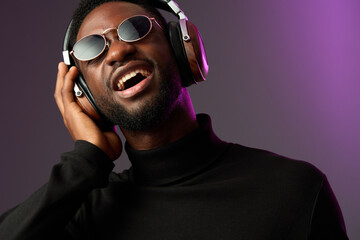 Young Black man enjoying music with headphones, wearing sunglasses, vibrant background, emotional...