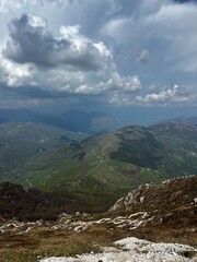 Scenic green hills with winding footpaths near Lake Como, Italy, under a dramatic cloudy sky on a spring day, showcasing natural beauty, peaceful landscape and rural outdoor travel destination