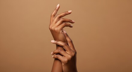 Elegant dark brown skin hands are posed gracefully against a brown background