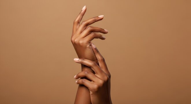 Elegant dark brown skin hands are posed gracefully against a brown background