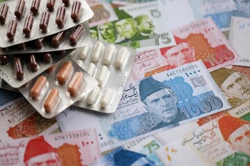 Pakistan rupees banknotes and medicine pills. Pakistan money bills with drugs close up