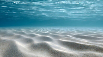 Underwater scene showcasing soft sandy ocean floor with gentle ripples, illuminated by sunlight filtering through clear blue water, creating a serene aquatic atmosphere