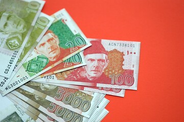 Pakistan rupees banknotes on red background. The current Pakistan money bills