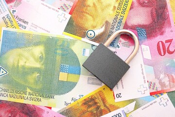 Swiss franc banknotes and padlock. The current francs money bills with lock lies in big amount