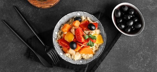 Bowl with couscous and vegetables on dark background