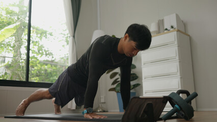 Asian man is performing push-ups at home as part of his strength and fitness routine.