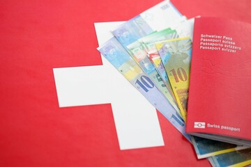 Swiss franc banknotes and passport with tickets on flag. The current francs money bills and pass