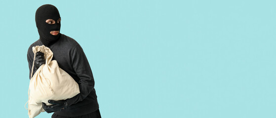 Male thief with bag on blue background