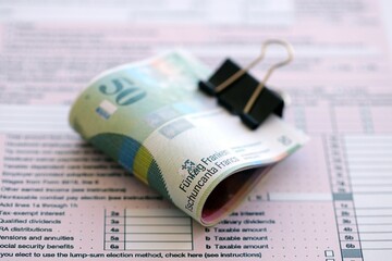 Swiss franc banknotes and tax form. The current francs money bills lies on tax return form