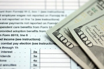 Hundred dollar bills and 1040 individual income tax return form blank close up