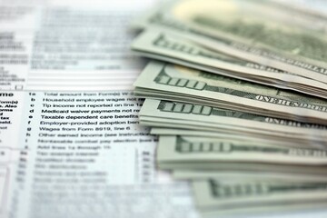Big amount of United States hundred dollar bills on table with tax return form close up