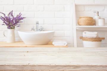 Light blurred bathroom background with mockup space for product display on bleached wooden table...