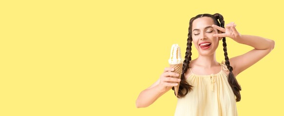Beautiful happy woman holding tasty ice cream and showing victory gesture on yellow background with space for text