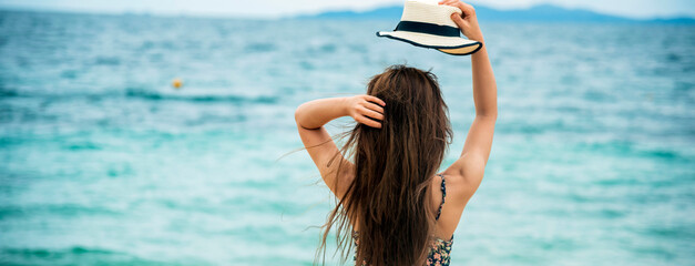 Naklejka premium Banner back side women standing on summer beach wear summer straw hat. Cheerful asian woman barefoot walking on tropical summer beach. Woman walking on beach relax freedom relaxation with copy space
