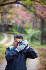 Vertical image Asian man use professional digital camera take a photo. Smiling male photographer...