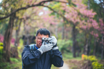 Asian man use professional digital camera take a photo. Smiling male photographer look at photo...