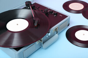 Record player with vinyl disks on blue table, closeup