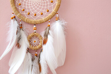 Dream catcher hanging on pink wall, closeup