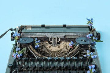 Vintage typewriter with flowers on blue background