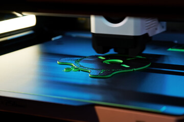 3D Printer in Action Creating a Detailed Object With Green Filament in a Modern Workspace