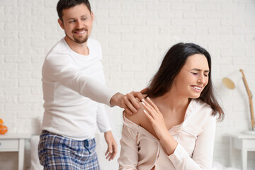 Crying young woman with her husband in bedroom. Domestic violence concept