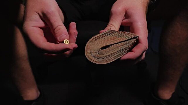 Symbolic slow motion capture of man holding currency and bullet in moody light