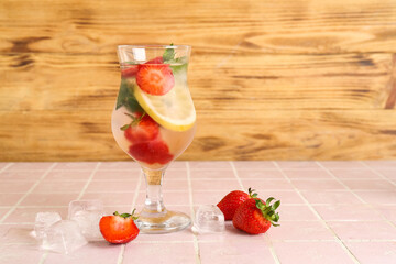 Glass of fresh lemonade with strawberry and lemon on pink tile table