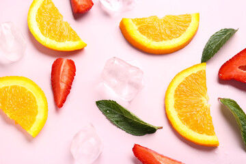 Orange slices with strawberries, ice cubes and mint on pink background