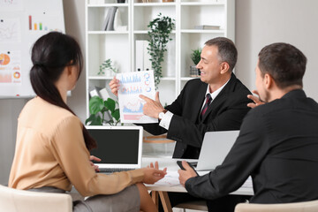 Business consultants working with diagrams at table in office