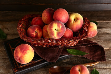 Wicker basket with sweet peaches on wooden background