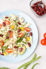 Plate of tasty pasta salad with tomatoes and beans on white background