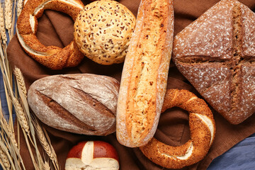 Different types of bread and wheat ears on blue wooden table