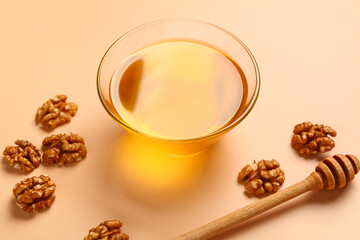 Glass bowl of sweet honey with walnut and dipper on beige background