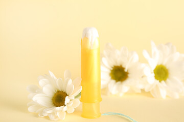 Menstrual tampon and beautiful chamomile flowers on color background